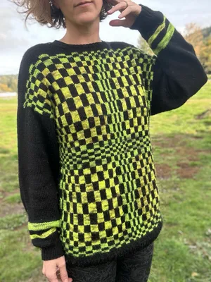 Stephanie wearing a black sweater with neon green distored checkers on the front
