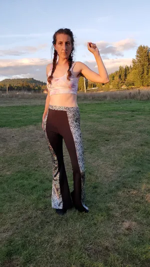 Stephanie wearing black bell bottoms with a wide holographic scribble stripe