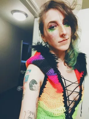 Stephanie in a crocheted onesie, made with fluorescent stripey yarn and a fuzzy hood