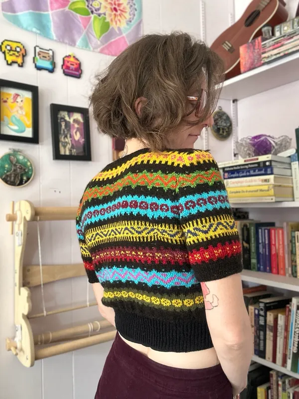 Short sleeve 40s style cropped sweater, with colorful bands of geometric stripes on a black background