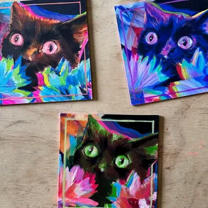three small square, colorful paintings of a startled black cat peeking out of glitchy flowers