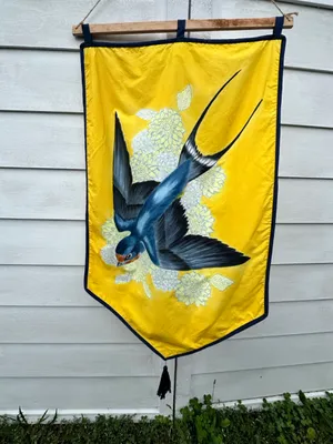 diving barn swallow over a field of white and yellow flowers on a yellow banner